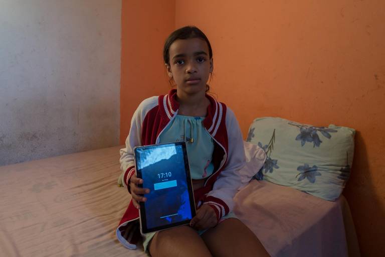 Emily, 10, diz ter dificuldade em usar o tablet fornecido pela prefeitura devido ao fraco sinal de internet no local onde ele mora, em Cidade Tiradentes, extremo da zona leste