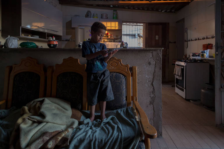 Bryan, 6, precisa ficar no andar de cima da casa para tentar pegar acesso de internet; cidade de São Paulo tem 100 mil alunos da rede municipal com dificuldade de acesso à internet