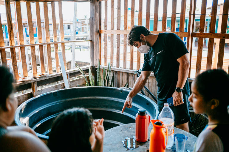 Felipe Gregório, fundador Florescer Brasil, examina caixa de água em casa de palafita em Macapá