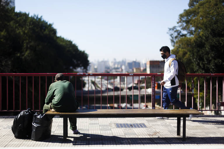 Homem observa trânsito, enquanto pedestre caminha pela rua Galvão Bueno, na Liberdade (centro de SP), na manhã desta segunda-feira (19), sem nenhum sinal indicativo sobre o início da Olimpíada de Tóquio 