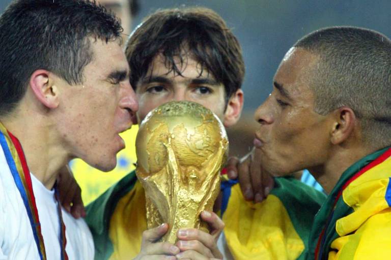 Os jogadores Lúcio, Kaká e Gilberto Silva beijam a taça após o Brasil conquistar o pentacampeonato, em Yokohama (Japão)