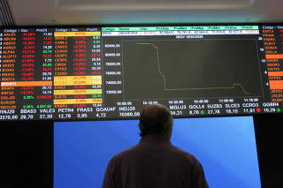 FILE PHOTO: A man stands in front of an electronic display at B3 Brazilian Stock Exchange in Sao Paulo