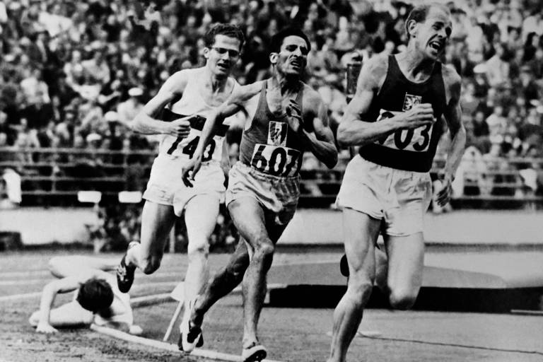 Tcheco Emil Zatopek corre na frente o francês Alain Mimoun e do alemão Herbert Schade durante a final dos 5.000 m dos Jogos de Helsinque; esta foi sua primeira medalha de ouro nessa edição, antes dos 10.000 m e da maratona