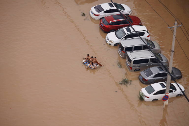 Grupo usa bote improvisado em rua alagada de Zhengzhou