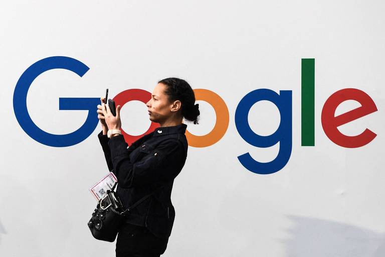 Mulher negra está de lado, segurando um telefone, na frente da logomarca do Google (escrita em letras coloridas)