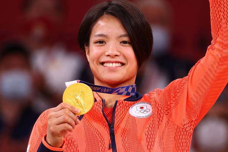 Sorrindo, a judoca japonesa Uta Abe segura coma mão direita a medalha de ouro que ganhou nas Olimpíadas de Tóquio, em 2021