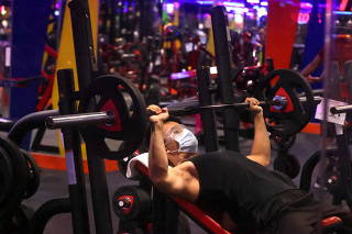 A man wearing protective face mask uses an equipment on the first day of the gym reopening