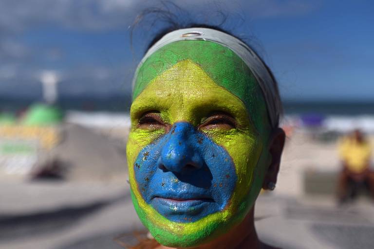 Manifestante com o rosto pintado com a bandeira do Brasil