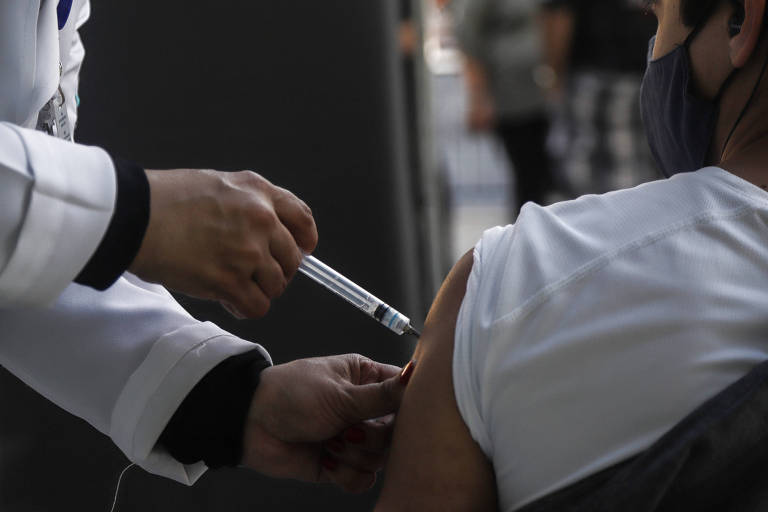Profissional da saúde aplica vacina no braço de uma pessoa