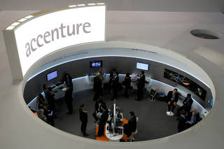 FILE PHOTO: Visitors look at devices at Accenture stand at the Mobile World Congress in Barcelona