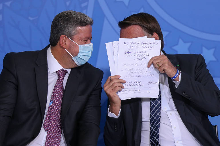 O presidente da Câmara, Arthur Lira (esq.), conversando e sentado ao lado do presidente Jair Bolsonaro, que cobre o rosto com papéis 