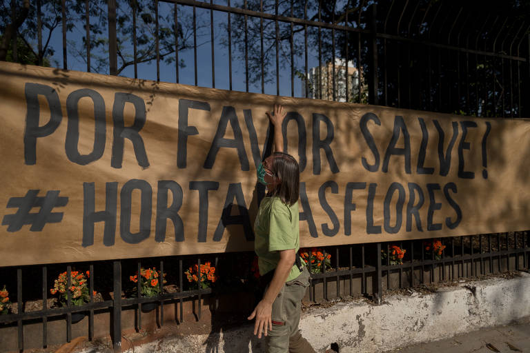 Faixa na frente do espaço Horta das Flores, no bairro da Mooca (zona leste da cidade de São Paulo), com a gestora ambiental da horta Regina Grilli.
