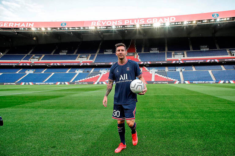Vestido com o uniforme do PSG, Messi segura a bola com a mão esquerda e posa para fotos no estádio Parque dos Príncipes