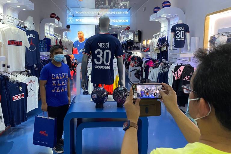 Fã tira foto com a camisa de Messi em loja oficial do PSG em Doha, no Qatar