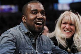 Recording artist Kanye West smiles as he sits courtside while attending the NBA basketball game between the Los Angeles Lakers and Chicago Bulls in Los Angeles