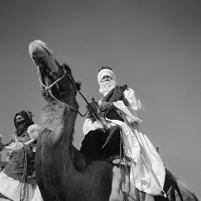 Homem com o rosto coberto em cima de camelo