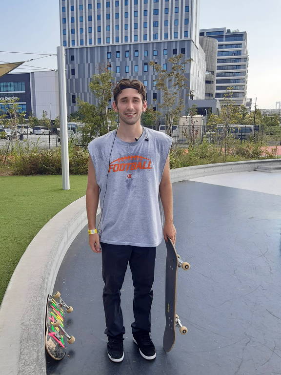 Homem de camisa regata posa para foto segurando um skate
