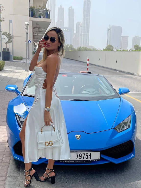 A influenciadora Laís Crisóstomo posa em frente a veículo azul em Dubai, nos Emirados Árabes.