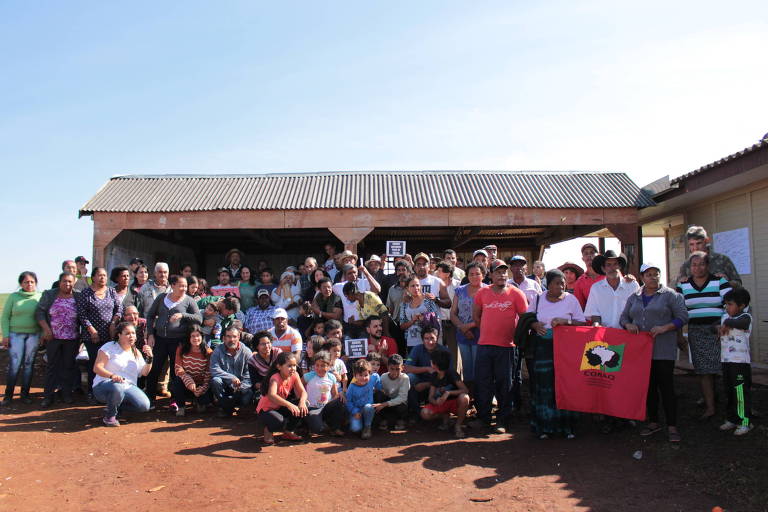 Dezenas de moradores da Comunidade posam para foto com títulos de terras e bandeiras do movimento nas mãos