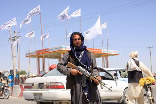 A Taliban fighter looks on as he stands at the city of Ghazni