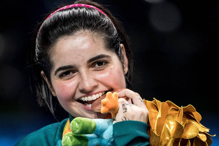 A mesa-tenista Bruna Alexandre morde a sua medalha de bronze das Paralimpíadas do Rio de Janeiro, em 201