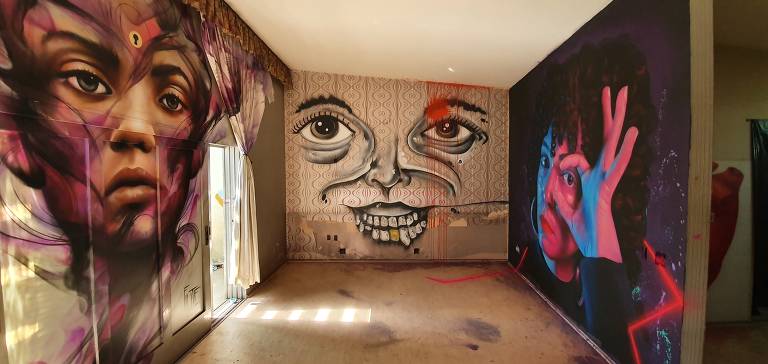 Três grafites com rostos em três paredes de quarto de casa