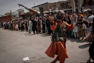 A Taliban fighter threatens a woman who was waiting to get access to the international airport with her family and others in Kabul, Afghanistan on Wednesday, Aug. 18, 2021. (Jim Huylebroek/The New York Times)