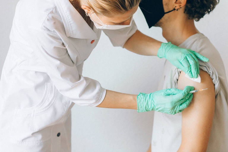Homem é vacinado no braço por uma enfermeira 