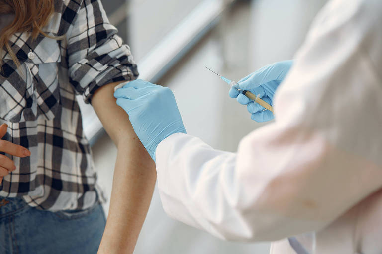 Menina é vacinada no braço por uma enfermeira 