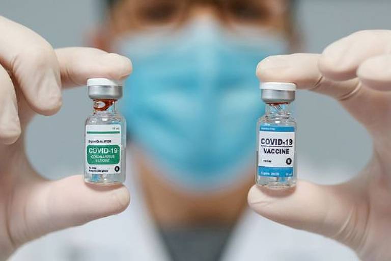 Um profissional da saúde de máscara mostra duas ampolas de vacina