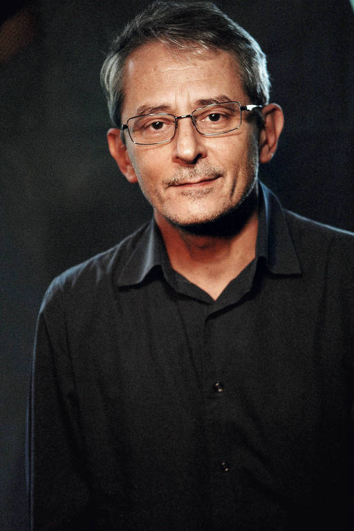 retrato de homem branco e magro, que usa óculos e veste camisa preta 