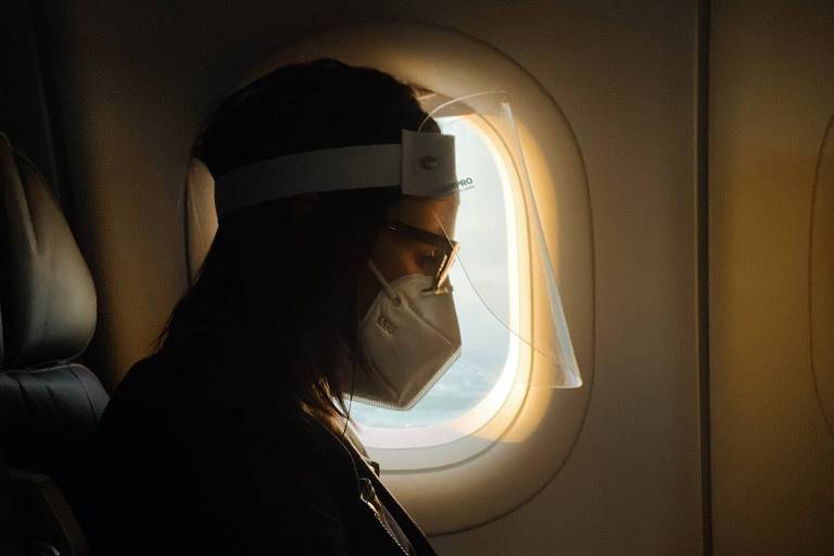Passageiro no avião com máscara e face shield