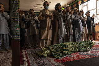 Men pray over the body of Hussain, a victim of the suicide bombing attack outside the international airport a day earlier, during his funeral at a mosque outside of Kabul, Afghanistan on Friday, Aug. 27, 2021. (Victor J. Blue/The New York Times)