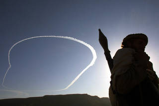 An American B-52 bomber circles above Afghanistan?s Tora Bora mountains as an anti-Taliban fighter stands armed with a rocket launcher on Dec. 12, 2001. (Joao Silva/The New York Times)