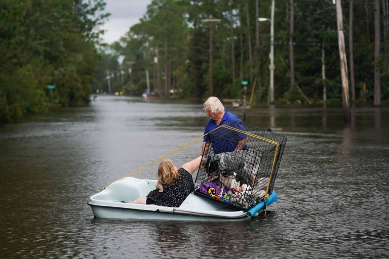 Casal usa barco para transportar cães em um bairro inundado no Mississippi