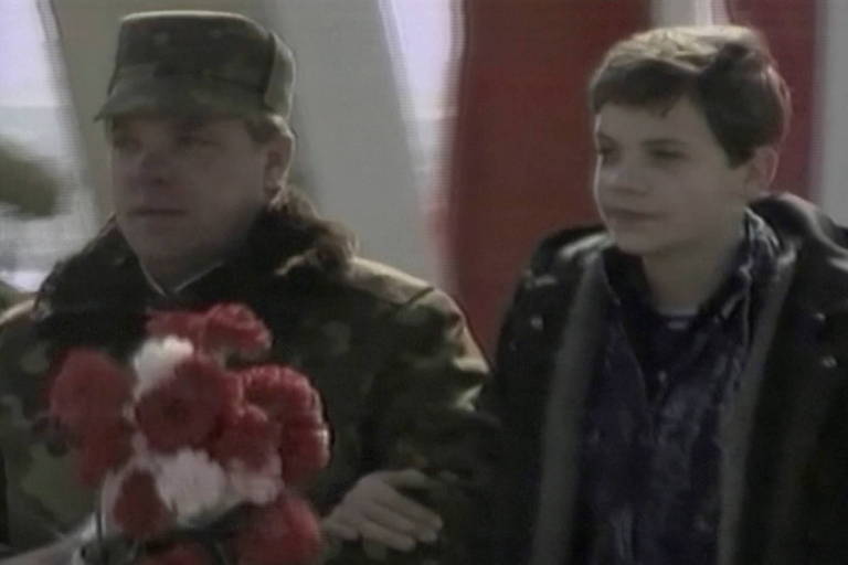 Boris Gromov, o último comandante do 40º exército da União Soviética no Afeganistão, carrega flores enquanto caminha em uma ponte ao lado do filho, durante a retirada das tropas soviéticas do país