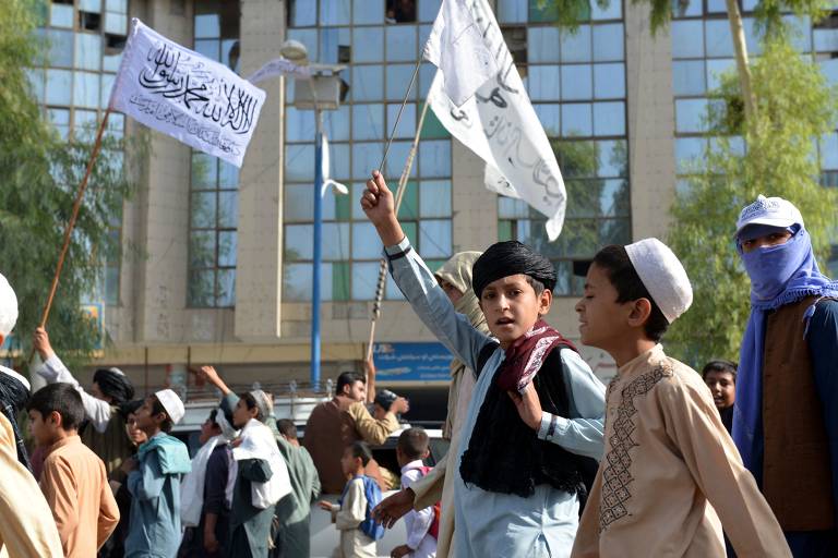 Jovens agitam bandeiras do Talibã e gritam slogans enquanto marcham por uma rua em Kandahar, segunda maior cidade do Afeganistão e onde o grupo fundamentalista estabeleceu a capital de seu regime durante o período em que esteve no poder pela primeira vez, de 1996 a 2001