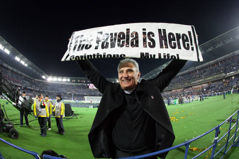 Tite erguendo faixa escrita "the favela is here"