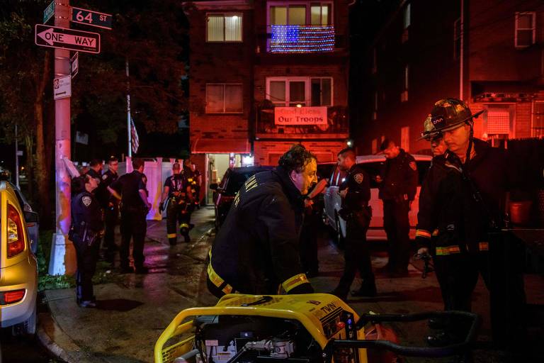 Policiais e equipes de resgate se reúnem do lado de fora de uma casa onde uma pessoa ficou presa em um porão inundado no Queens, em Nova York