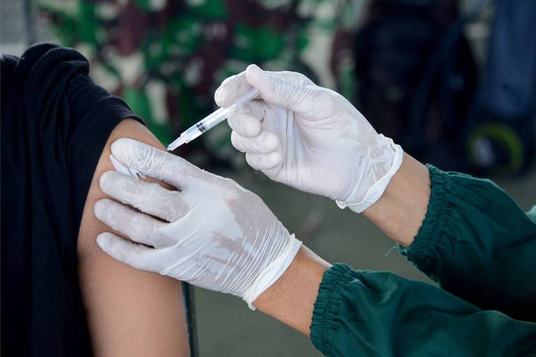Profissional aplica vacina em jovem