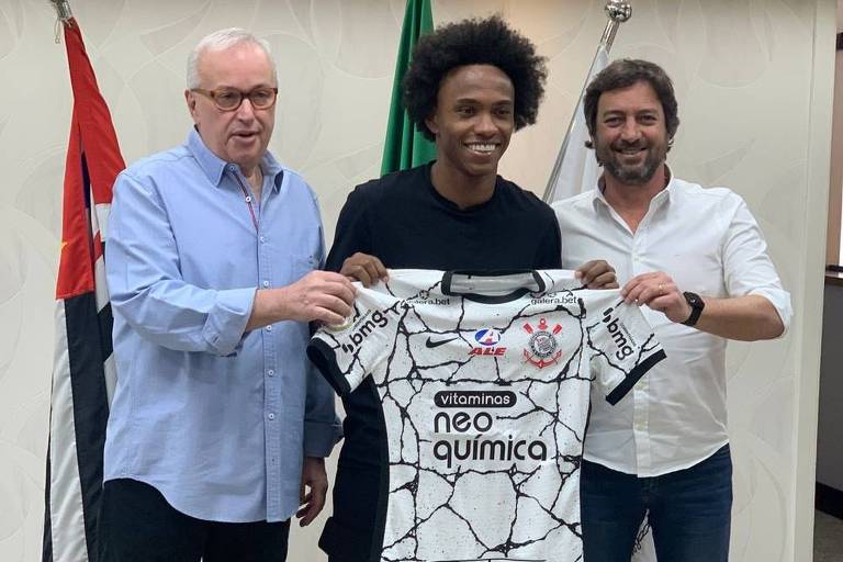 Willian, reforço do Corinthians, mostra a camisa da equipe entre o presidente Duilio Monteiro Alves (à dir.) e o diretor de futebol Roberto de Andrade