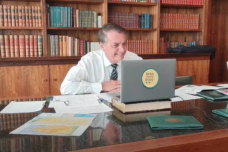Jair Bolsonaro e adesivo no notebook com slogan em teste para 2022