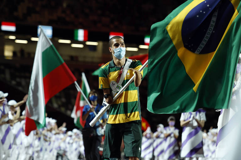 Daniel carrega bandeira do Brasil vestido com uniforme listrado em verde e amarelo