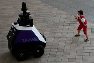 School children chase after autonomous robot Xavier, as it patrols a neighbourhood mall to detect 