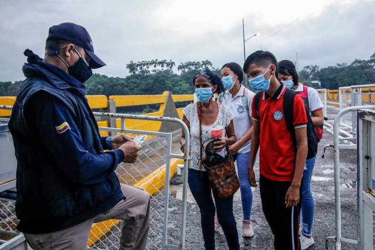 Oficial de migração checa documentos de estudantes venezuelanos após eles cruzarem a ponte Simon Bolivar, que liga a Venezuela à Colômbia