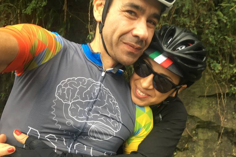 homem e mulher com capacete de ciclista posam para foto