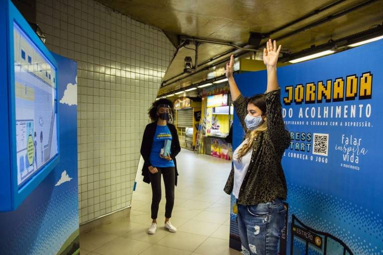Passageira do metrô brinca com o game da campanha Jornada do Acolhimento, na estação Paulista