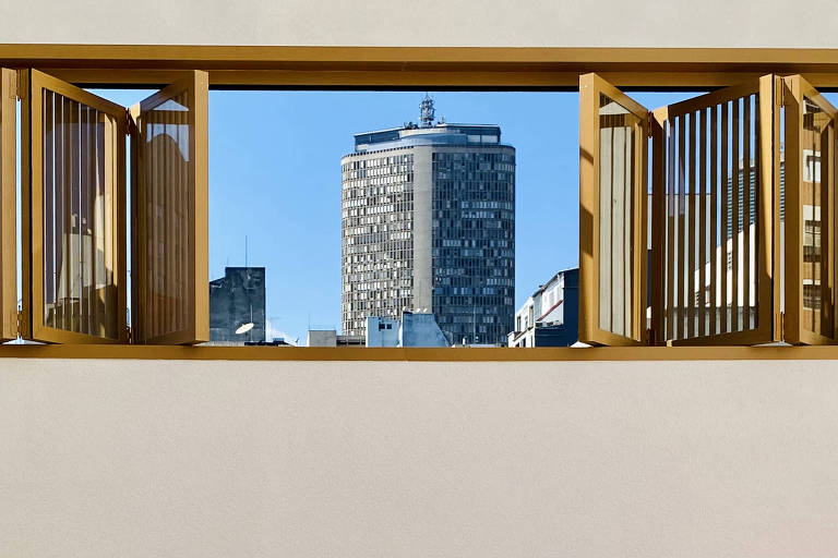 De janela de madeira aberta é possível ver prédios