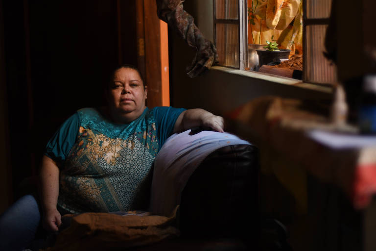 Kelcilene de Souza, sentada no sofá de sua casa, é empregada doméstica e ficou sem trabalho durante a pandemia