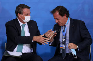 Jair Bolsonaro durante cerimônia com o presidente da Caixa, Pedro Guimarães